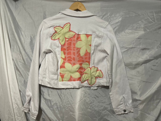 Light-colored jacket with floral patterns on a hanger against a plain background
